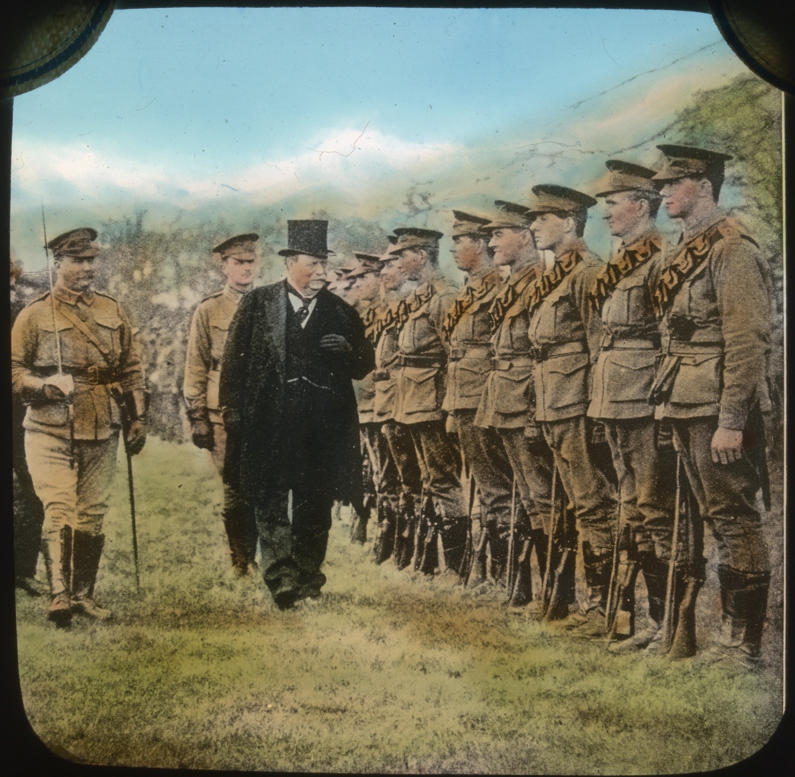 Colourised photographt of man wearing top hat and tails inspecting lined up troops