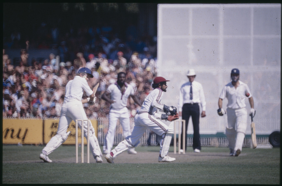 Cricket match in progress at the Melbourne Cricket Ground, players at the crease, umpire, crowded grandstand