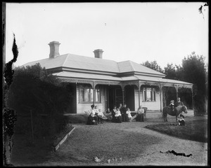 Women, children and small pony in front of residence