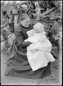 Portrait of woman in black dress holding young child