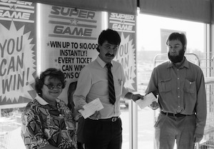 Two customers prize winners receiving cheques from man Super Game promotion Coles New World